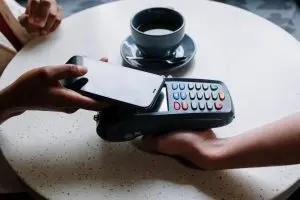 Someone using a card machine and a mobile phone to make a payment