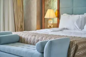 A hotel bed, with a lamp beside it