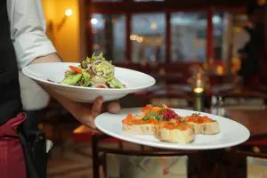 Two plates held by a waiter in one hand