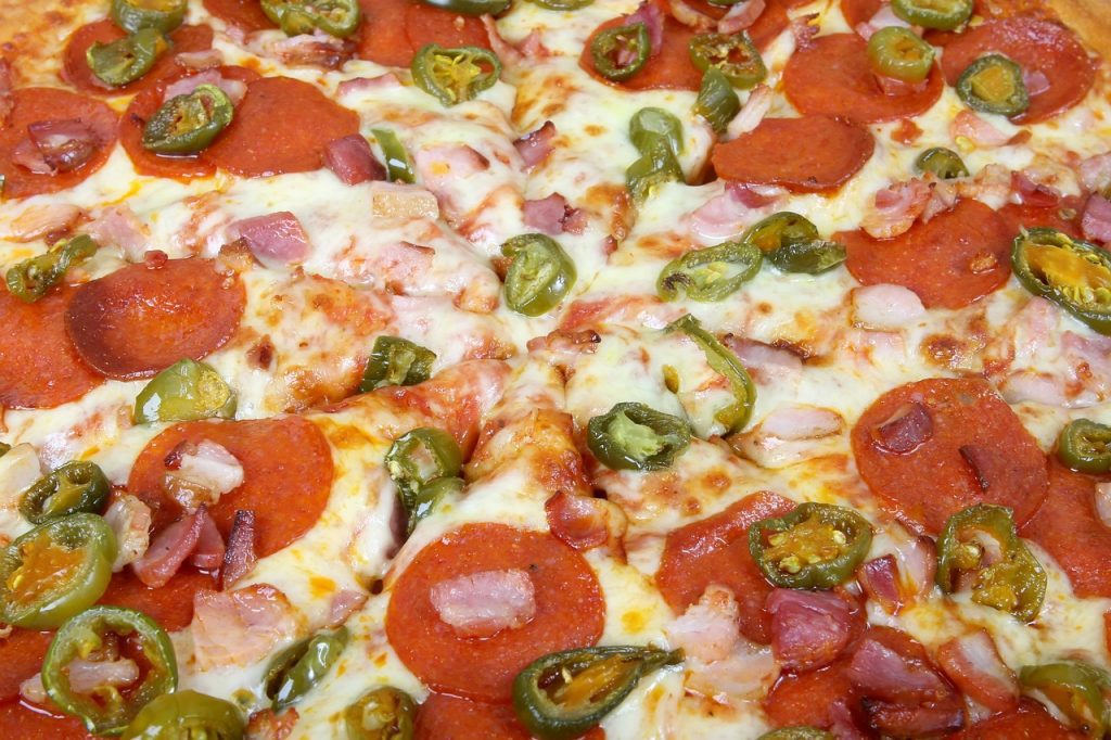 close-up of a pizza with cheese, meat and jalapenos