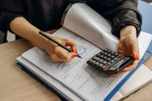 A person holding a pen and a calculator